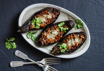 Stuffed lentils roasted eggplant - delicious healthy vegetarian lunch, snack, appetizer on a dark background, top view