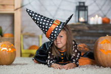 Happy Halloween. A Little Beautiful Girl In A Witch Costume Celebrates A Home In An Interior