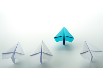 Business leadership concept with blue paper plane leading among white.