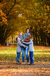 © gorynvd - Young happy mother with her three smiling sons wearing denims and walking in the autumn park. Mom with her children on the autumn background.
