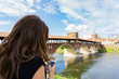 Girl using phone near Ponte coperto ( covered bridge ) over Ticino river in Pavia, Lombardy, Italy