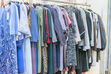 Colorful women's dresses on hangers in a retail shop. Fashion and shopping concept. Hanger with clothes in the store