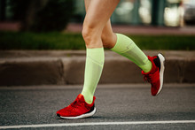 Women Feet Runner In Green Compression Socks And Red Running Shoes
