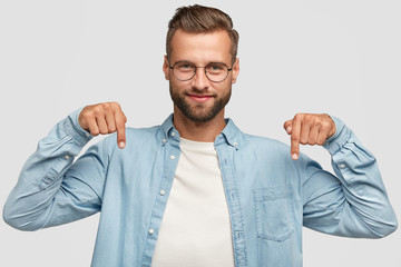 lets go downstairs. photo of attractive unshaven man with appealing look, points down with both inde