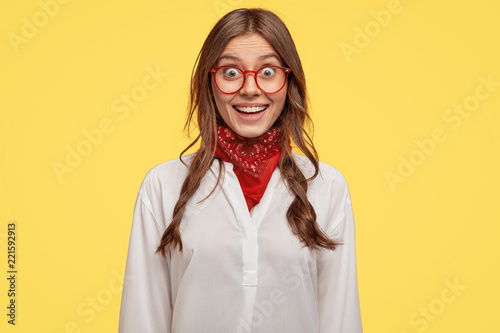 Fotografía Cheerful student with amazed happy expression, has dark hair, dressed in white shirt, isolated over yellow background