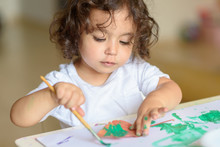 Summer Or Autumn.Cute Little Girl Drawing With Green Paint On Fall Lives. Curly Adorable Child Painting At Table.