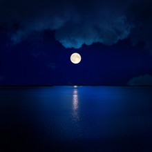 Full Moon In Clouds Over Water