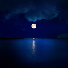 full moon in clouds over water