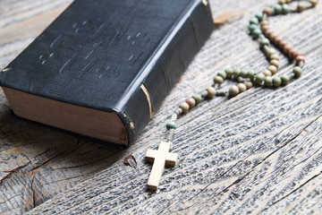 Bible and rosary on wood