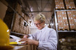Young female worker is looking at documents with satisfaction in a storage room.