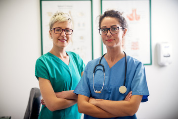 Portrait of two professional nurses standing in their office in front of a camera.