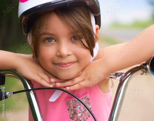 Fotografie, Obraz Close-up of a little girl's face on bike looking at camera and smiling