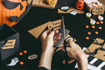 Halloween preparation. Hands making halloween cards using craft paper