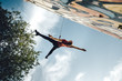 Dancer performing aerial dance on urban scenery at sunset against blue sky