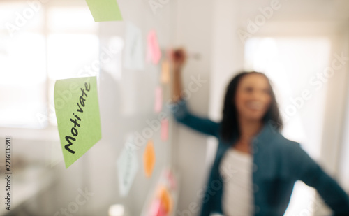 Fotomural Sticky note with motivate written on it pasted on glass wall