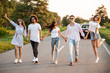 © Leika production - Young stylish two guys and three girls are  holding hands and walking on the road on a sunny day