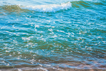 pure azure clear water with white foam on the sea on a sunny afternoon, blurry background