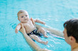 © Irina Schmidt - Happy middle-aged father swimming with cute adorable baby in swimming pool. Smiling dad and little child, newborn girl having fun together. Active family spending leisure and time in spa hotel