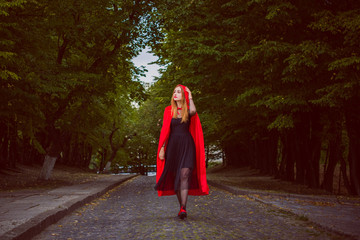  Concept of Halloween. Beautiful and simple costume of little red hood. Mysterious hooded figure in misty forest. Girl in red raincoat. Cosplay Fairy Tale Little Red Riding Hood 