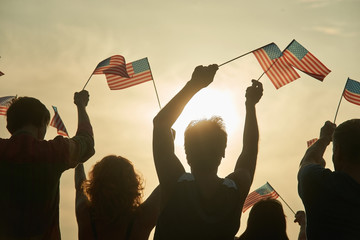 Wall Mural - Crowd of people holding american flag, back view. Silhouette of patriotic usa crowd, rear view.