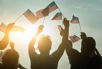 Wall Mural - American elections concept. People raising usa flags up to the sky.