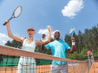 © Yakobchuk Olena - Happy man and woman are playing sport on court together in one team. They are standing near net and raising arms with rackets. They are expressing bliss after winning set