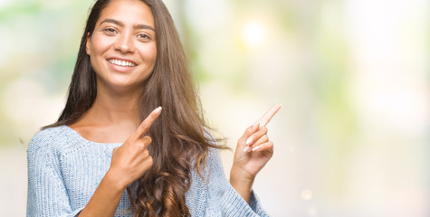 Young beautiful arab woman wearing winter sweater over isolated background smiling and looking at the camera pointing with two hands and fingers to the side.