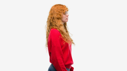 Wall Mural - Young redhead woman wearing red sweater looking to side, relax profile pose with natural face with confident smile.