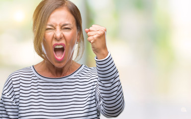 Poster - Middle age senior hispanic woman over isolated background angry and mad raising fist frustrated and furious while shouting with anger. Rage and aggressive concept.