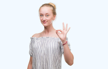 Wall Mural - Blonde teenager woman wearing a bun doing ok sign with fingers, excellent symbol