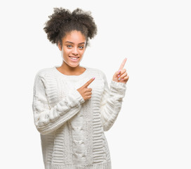 Young afro american woman wearing winter sweater over isolated background smiling and looking at the camera pointing with two hands and fingers to the side.