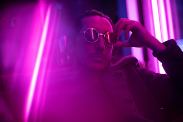 Long hair girl with sunglasses and leather jacket looking at neon lights