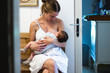 © Alexander - young mother sitting in hallway and breastfeeding her baby in her arms