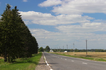 Asphalt road leaves in perspective among green, fields on roadsides and clear blue sky on a summer day - travel, tourism, country landscapemn highway in october gray day