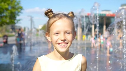 little adorable girl have fun in street fountain at hot sunny day