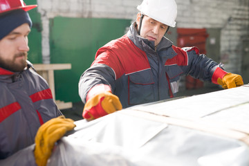 Wall Mural - Portrait of mature factory worker wearing hardhat packaging shipment units in industrial workshop, copy space