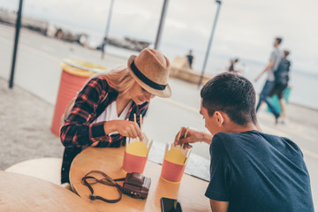 Poster - Young man and woman having Asian food in boxes on street eating with chopsticks while sitting at table on street