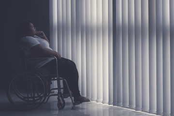 Pensive obese woman sitting in the wheelchair