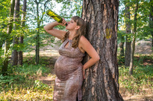 Pregnant Woman Drinking Wine In The Park - Alcoholism Concept