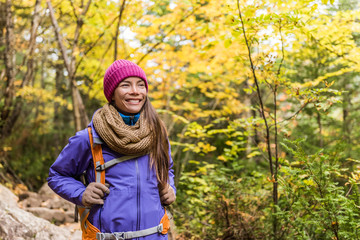 happy asian woman hiking in autumn forest nature walking on trail path. hiker girl with backpack, ha