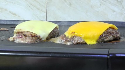 Poster - Swiss and cheddar cheese melting on hamburgers on a grill
