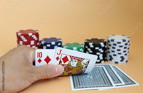 фотография close up of female hands with casino chips and playing cards making bet or takin