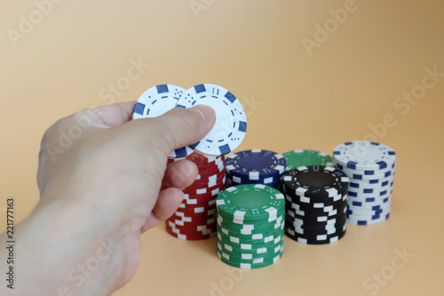 фотография Hands holding two casino chips with a pile of casino chips.
