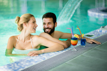 Wall Mural - Happy attractive couple relaxing in swimming pool