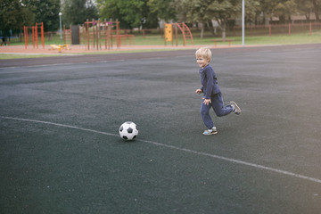 active lifestyle in a modern city - little boy playing with a soccer ball at the stadium