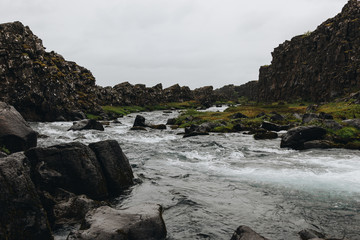 Wall Mural - beautiful mountain river flowing through highlands under cloudy sky in Thingvellir national park in Iceland