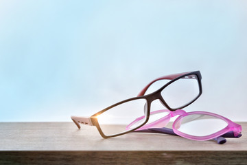 Wall Mural - Two eyeglasses on wood table with blue background