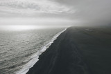 Fototapeta Nowy Jork - wavy ocean and coastline of black sand beach under cloudy sky in Vik, Iceland