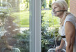 Elder person with an oxygen breathing mask looking at a window
