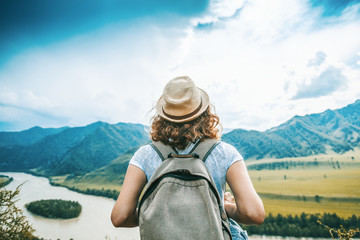 Wanderlust and travel concept. stylish traveler woman in hat looking at mountains. hipster girl traveling on top of mountain, looking in front. space for text. atmospheric moment